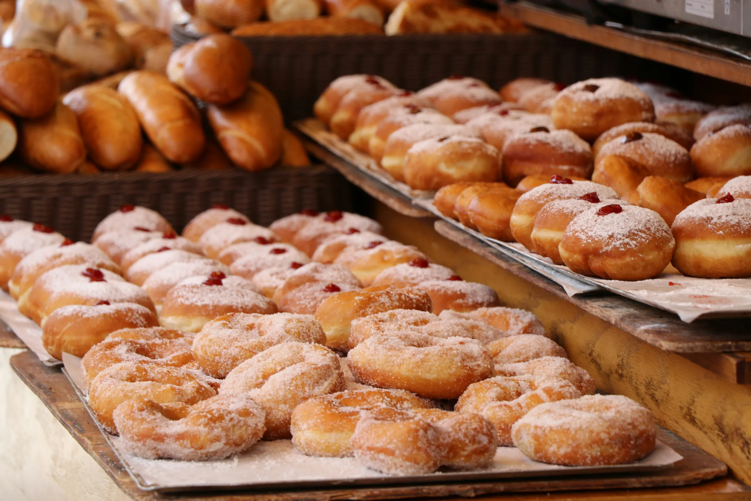 Świeże pączki i drożdżówki oprószone cukrem pudrem na tacach